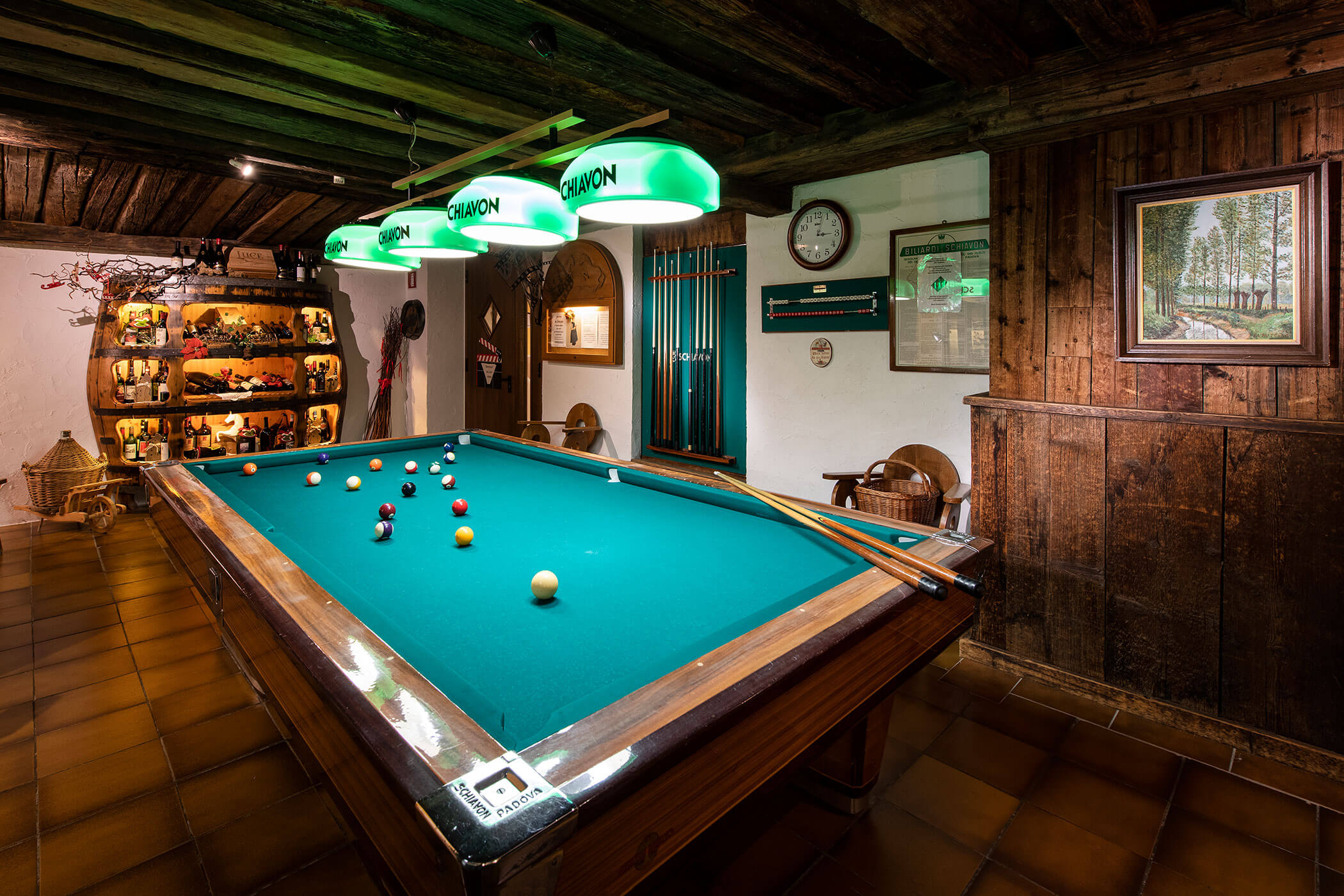Un tavolo da billiard in una stanza illuminata da alcune lampade.