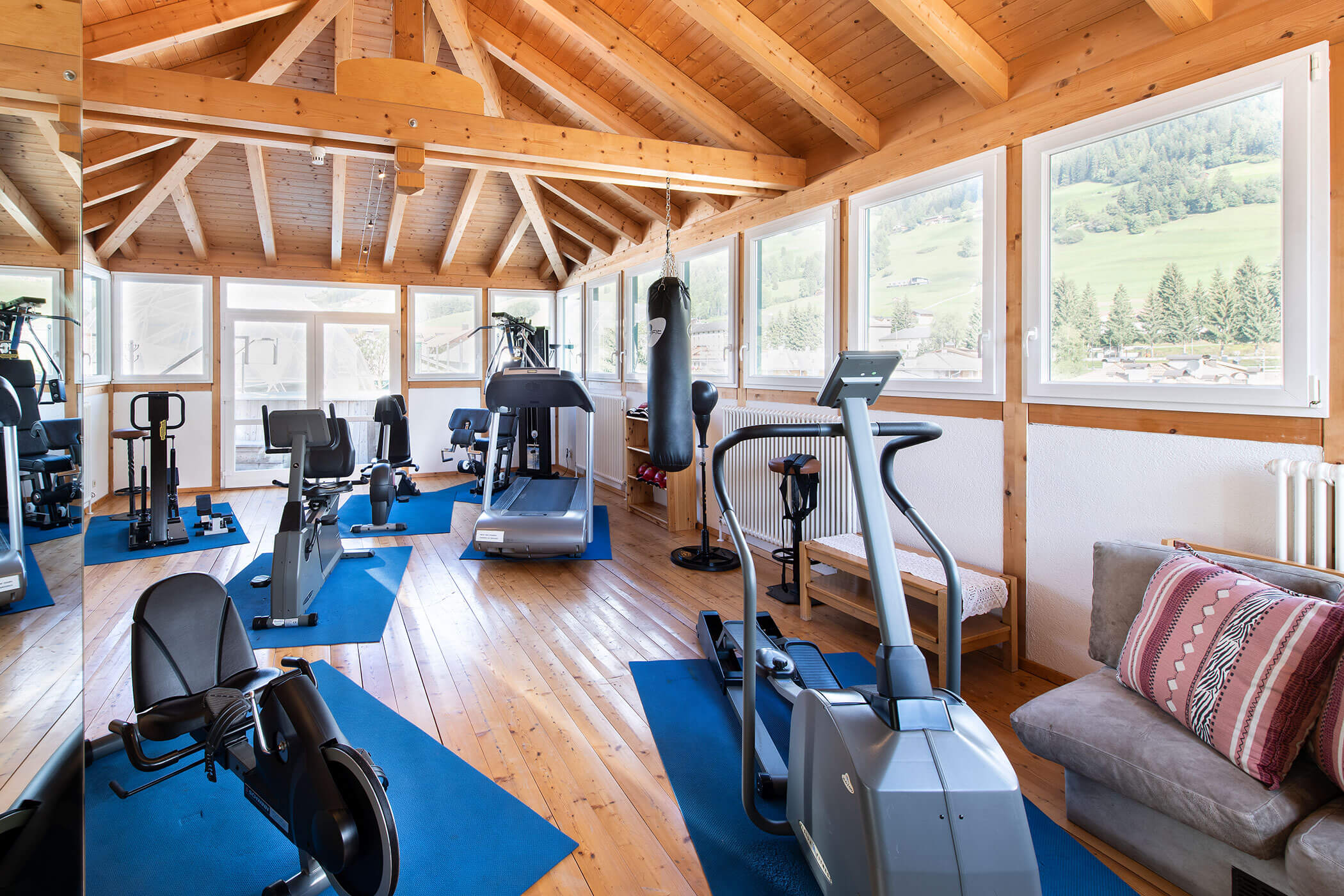 Una stanza di palestra con attrezzature per esercizi e un divano.