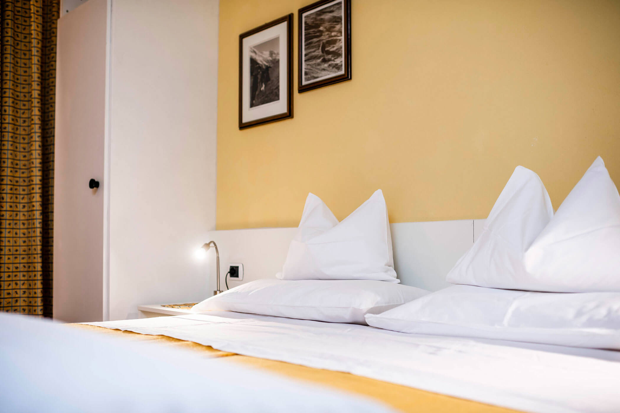 Un letto con cuscini bianchi e lenzuola gialle.