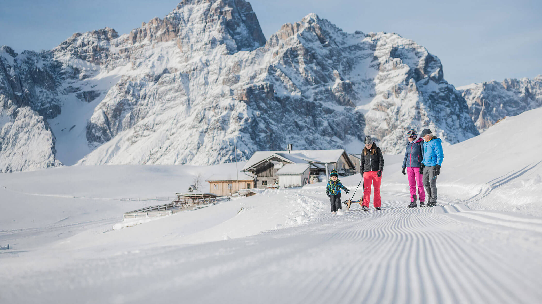 Quattro persone camminano sulla neve con un slittino.