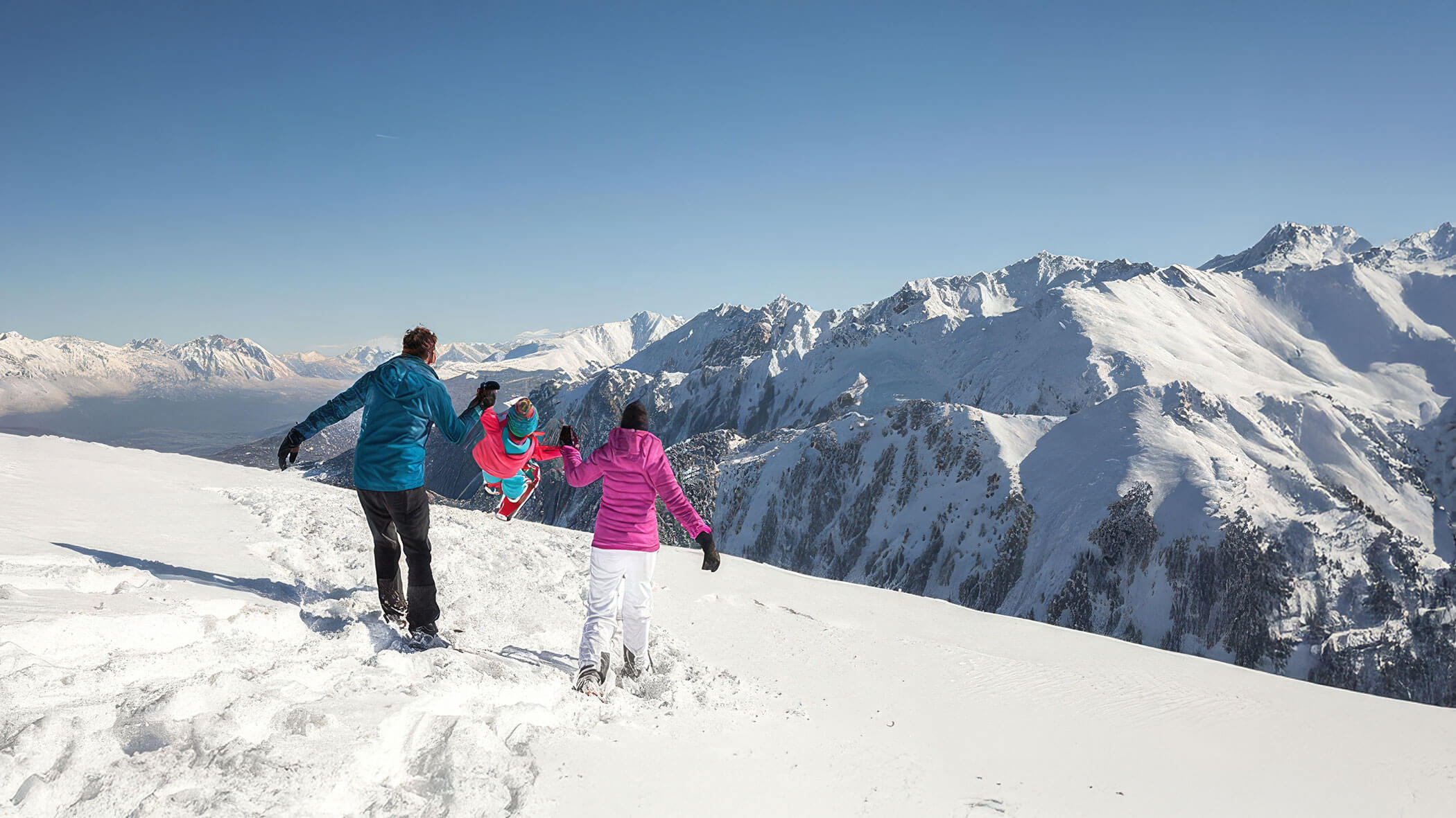 Un gruppo di persone cammina su una montagna innevata, circondato da paesaggi bianchi e alberi coperti di neve.