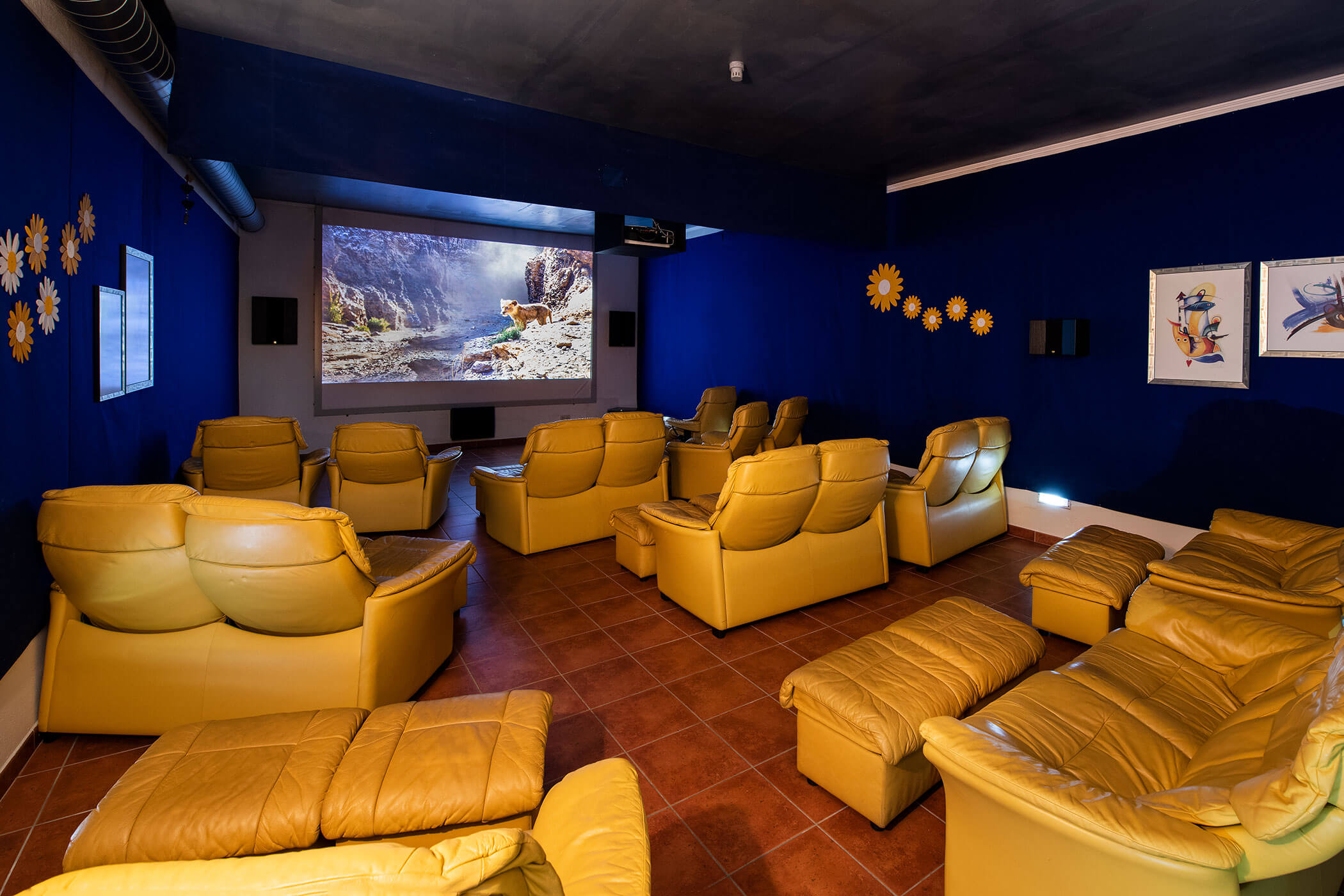 Una cinema con poltrone in pelle gialla e un grande schermo.