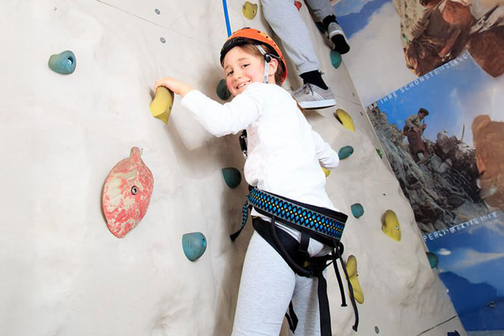 Una giovane ragazza sta scalando una parete di roccia.