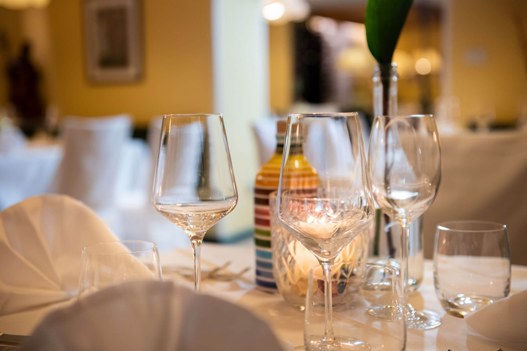 Un tavolo apparecchiato con bicchieri di vino e tovaglioli ben piegati.