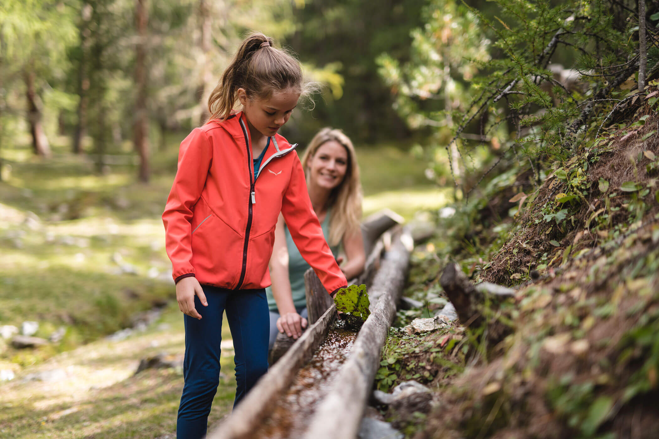 Una donna e una bambina sono in piedi su un corrimano di legno.